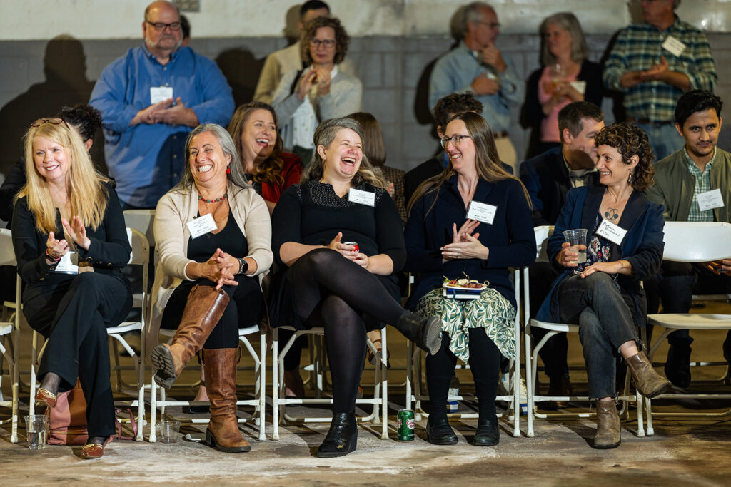 Group of seated women smiling and laughing.