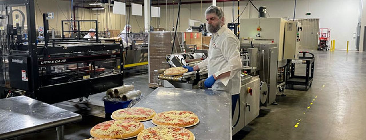 a man in an industrial kitchen making pizza