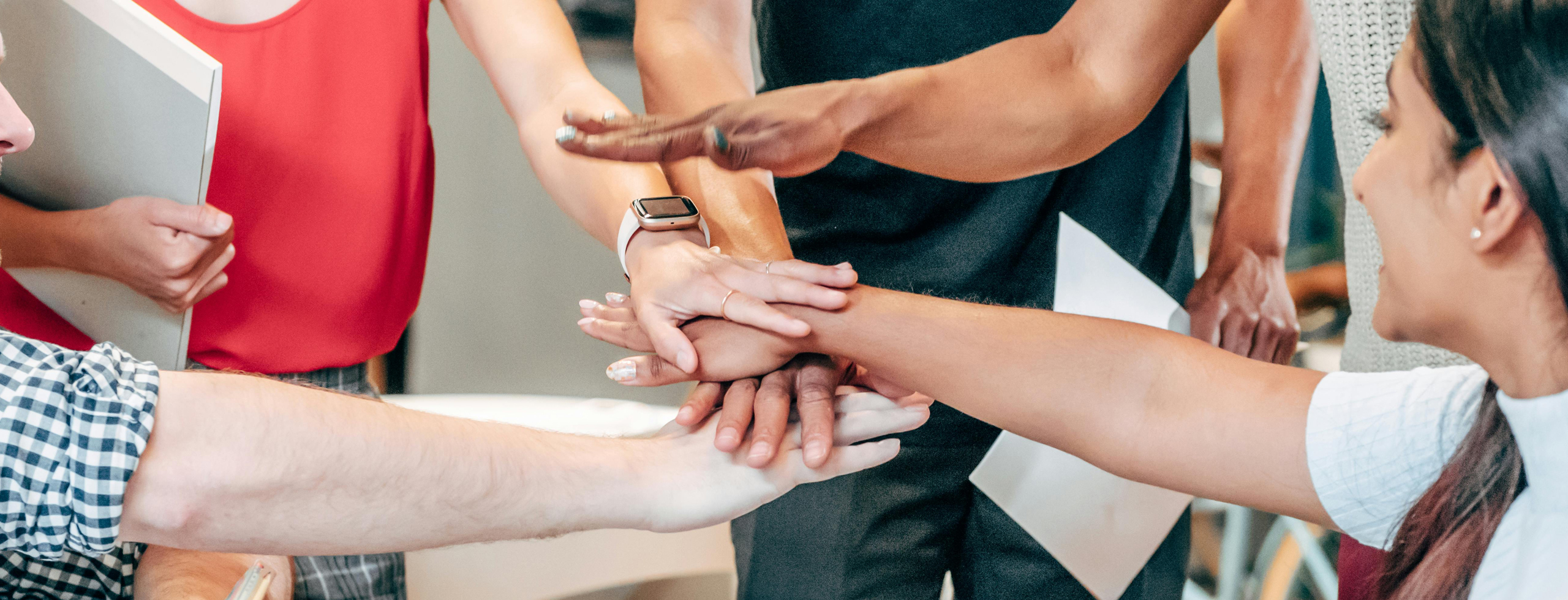 a group of people who have held out their hands and stacked them with others
