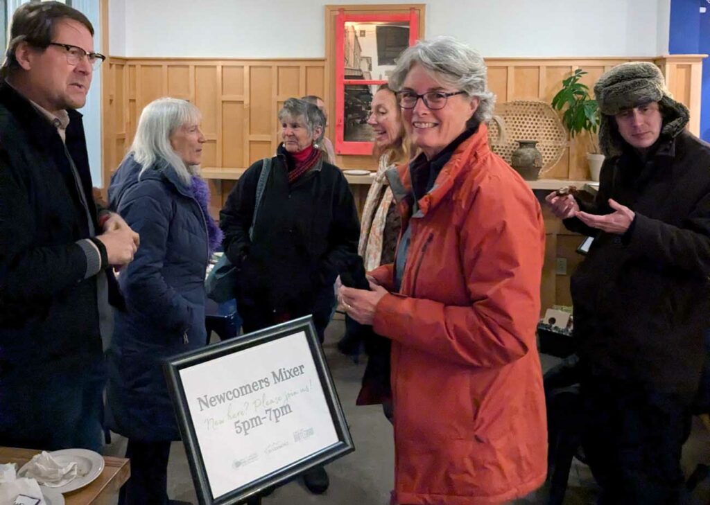 A small group of people at a mixer event wearing winter coats.|