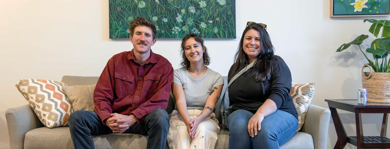 three people sitting on a couch and smiling