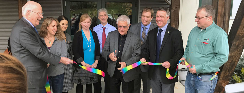 a group of smiling people at a ribbon cutting
